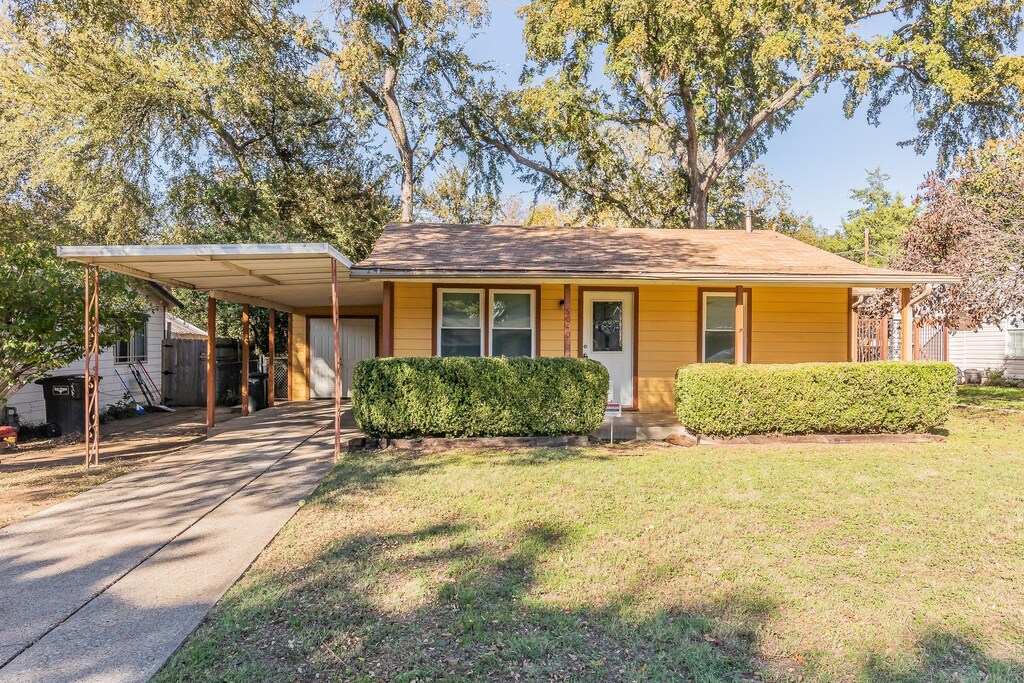 view of front facade with a front lawn, a porch, and a carport