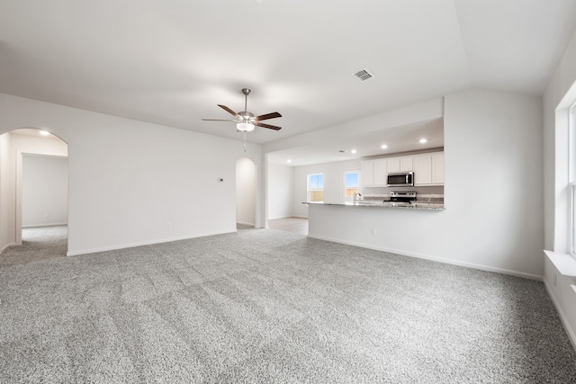 unfurnished living room with ceiling fan, sink, and light carpet