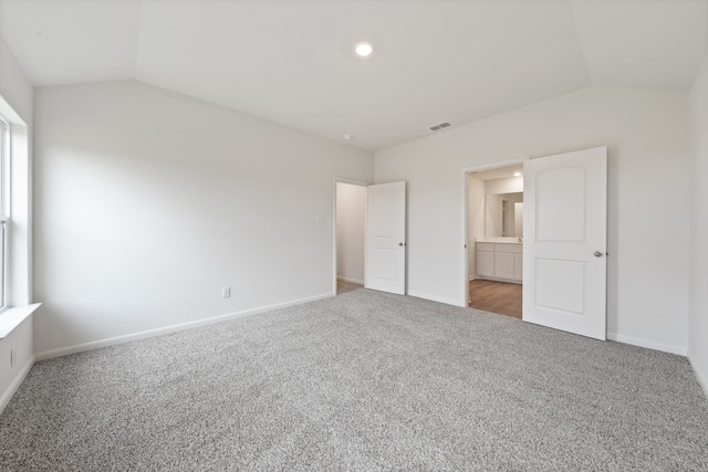 unfurnished bedroom featuring carpet floors, connected bathroom, and vaulted ceiling