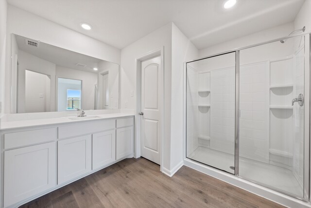 bathroom with hardwood / wood-style floors, vanity, and an enclosed shower