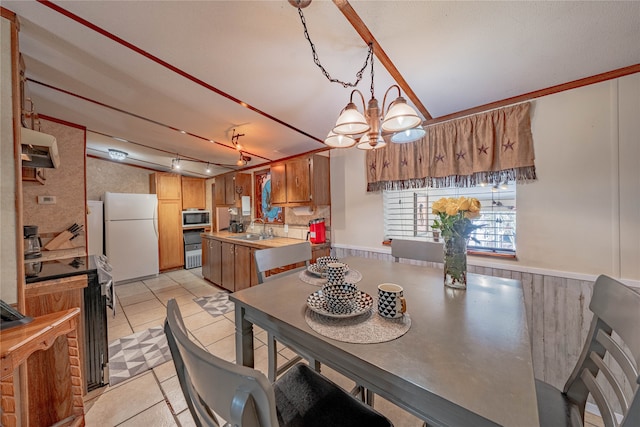 tiled dining room featuring sink, track lighting, and a notable chandelier