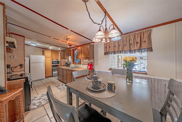 tiled dining room featuring sink, track lighting, and a chandelier