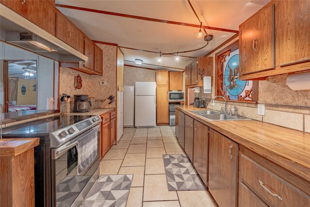 kitchen with light tile patterned flooring, appliances with stainless steel finishes, range hood, sink, and decorative backsplash