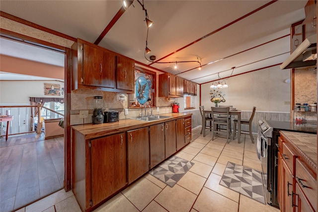 kitchen featuring vaulted ceiling with beams, sink, decorative backsplash, a notable chandelier, and stainless steel electric range