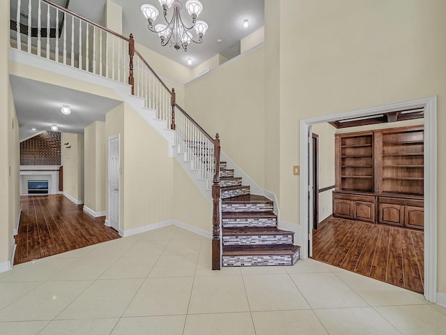 stairway with built in shelves, a high ceiling, a notable chandelier, hardwood / wood-style floors, and a fireplace