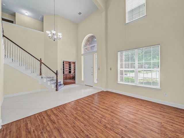 entrance foyer featuring a towering ceiling, light hardwood / wood-style floors, and a notable chandelier