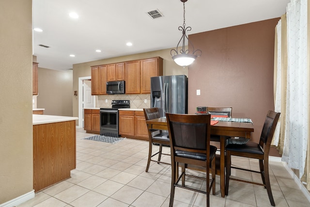 kitchen featuring decorative backsplash, light tile patterned floors, hanging light fixtures, and appliances with stainless steel finishes