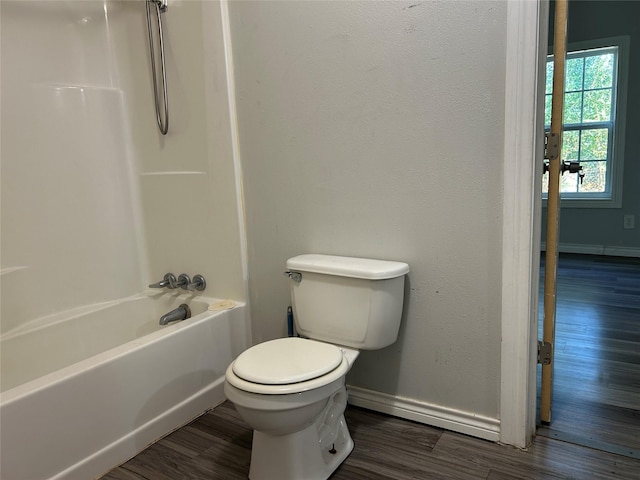 bathroom with hardwood / wood-style floors, shower / bathing tub combination, and toilet