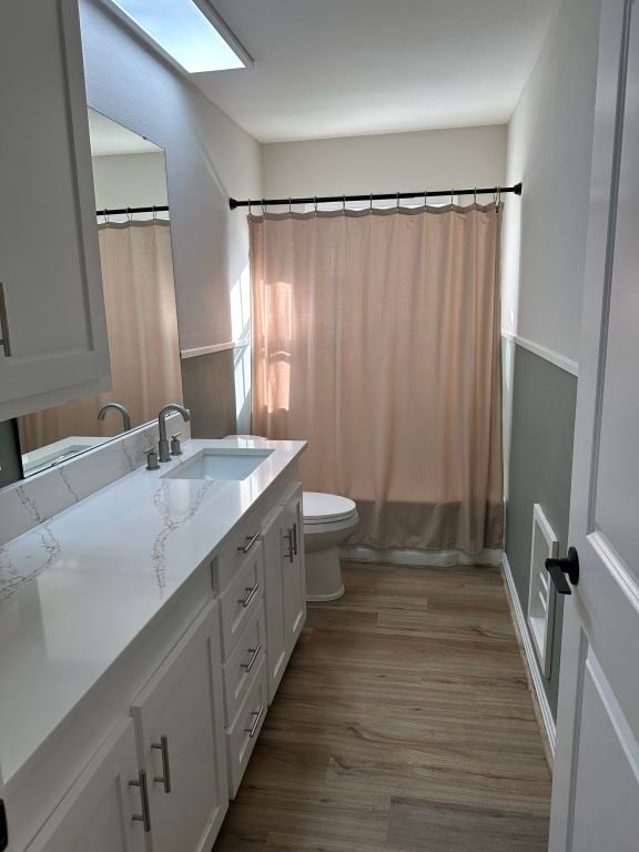 full bathroom featuring vanity, hardwood / wood-style flooring, toilet, and shower / tub combo with curtain