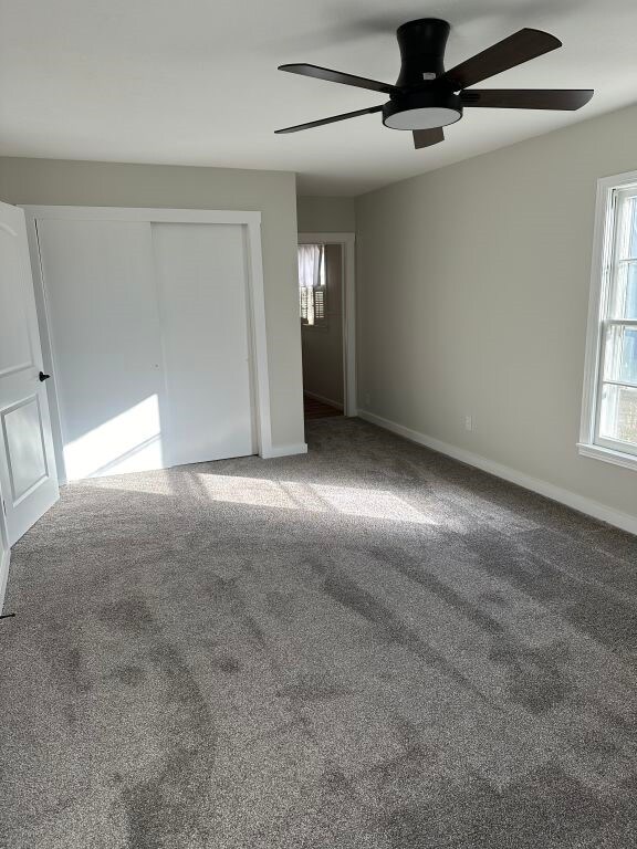 unfurnished bedroom featuring carpet flooring, a closet, and ceiling fan