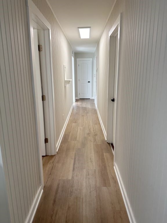 corridor featuring crown molding and light hardwood / wood-style flooring