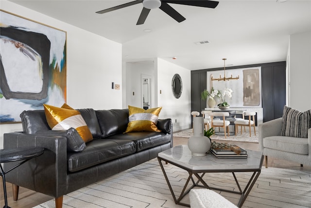 living room featuring ceiling fan with notable chandelier and light hardwood / wood-style flooring