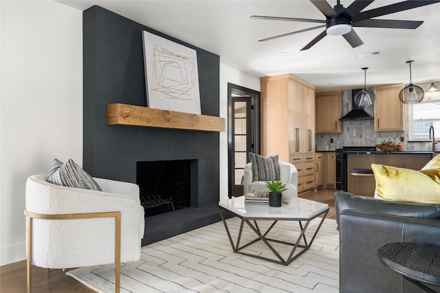 living room featuring a fireplace, light hardwood / wood-style floors, and ceiling fan