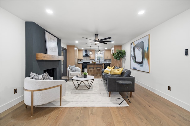 living room with ceiling fan, a fireplace, and light hardwood / wood-style flooring