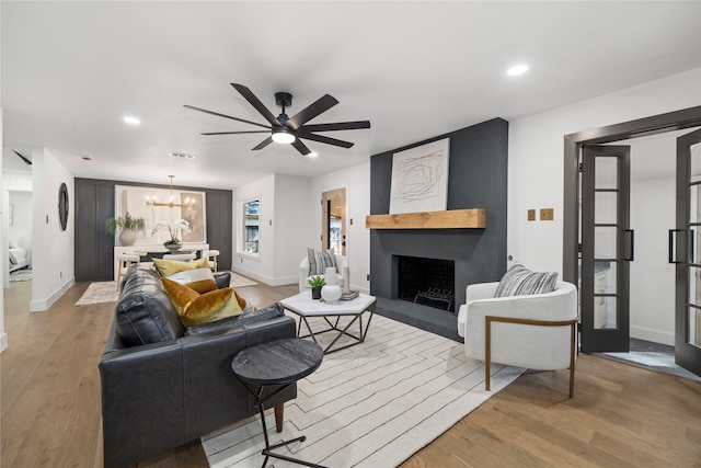 living room with light hardwood / wood-style flooring and ceiling fan with notable chandelier