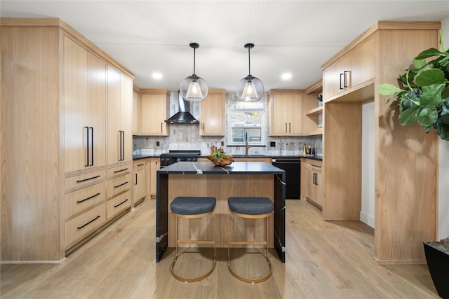 kitchen featuring light brown cabinets, black appliances, wall chimney range hood, decorative light fixtures, and light hardwood / wood-style floors