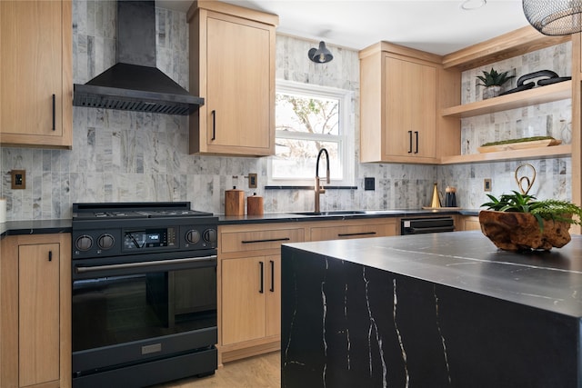 kitchen featuring stainless steel counters, sink, light brown cabinets, wall chimney range hood, and black range with gas stovetop