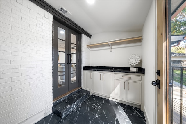 doorway with plenty of natural light, brick wall, and vaulted ceiling