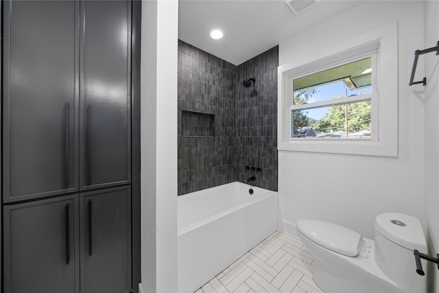 bathroom featuring tile patterned flooring, toilet, and tiled shower / bath