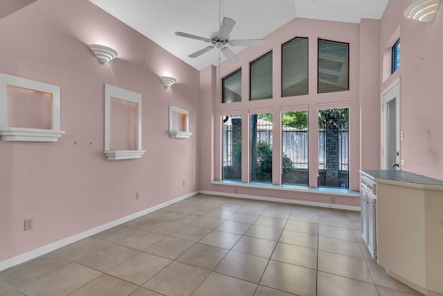 tiled empty room featuring ceiling fan, high vaulted ceiling, and a textured ceiling