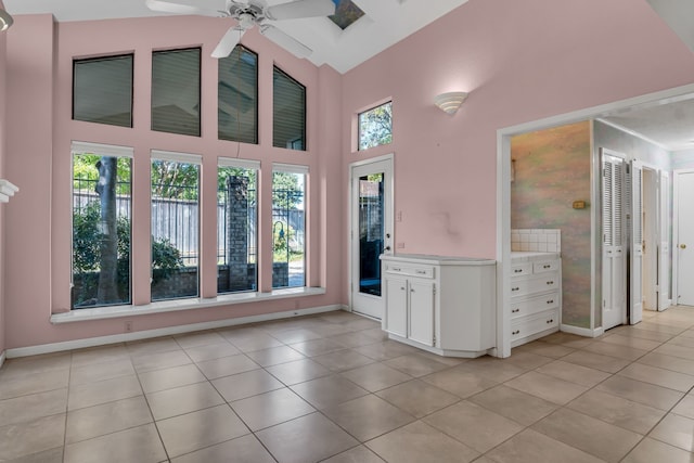 interior space featuring white cabinets, light tile patterned floors, high vaulted ceiling, and ceiling fan