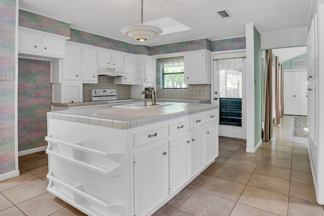 kitchen featuring tile countertops, white cabinets, custom range hood, and sink