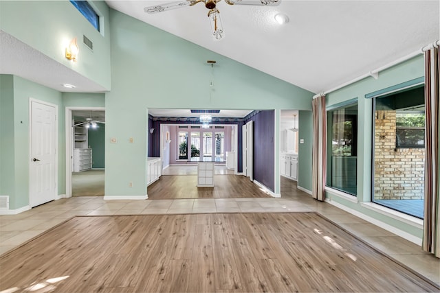 interior space featuring light tile patterned floors, a textured ceiling, vaulted ceiling, and ceiling fan