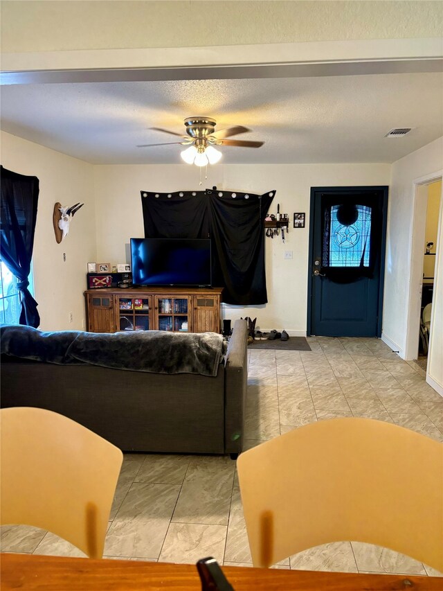 living room featuring ceiling fan and a textured ceiling