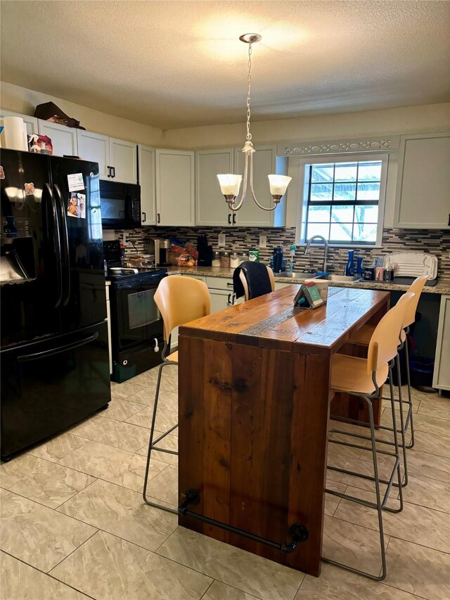 kitchen featuring an inviting chandelier, decorative light fixtures, a breakfast bar, a kitchen island, and black appliances