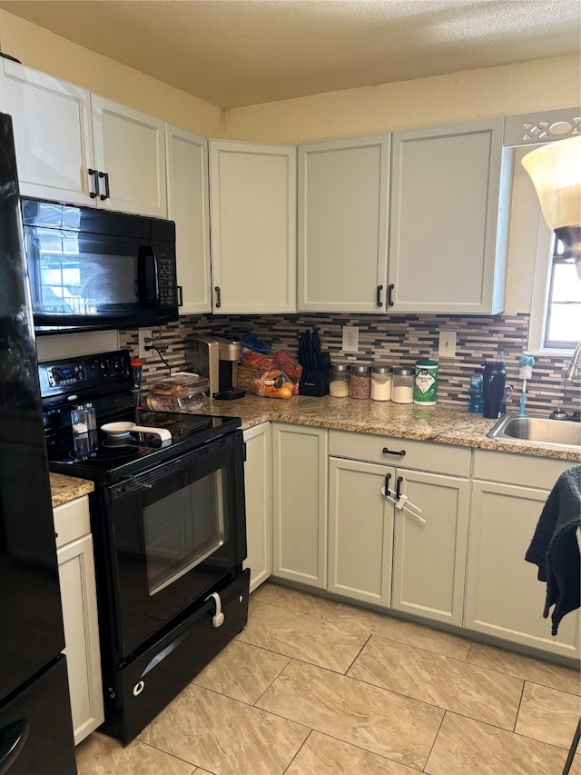 kitchen with sink, light stone counters, backsplash, white cabinets, and black appliances