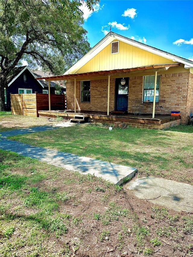 rear view of property featuring covered porch and a yard