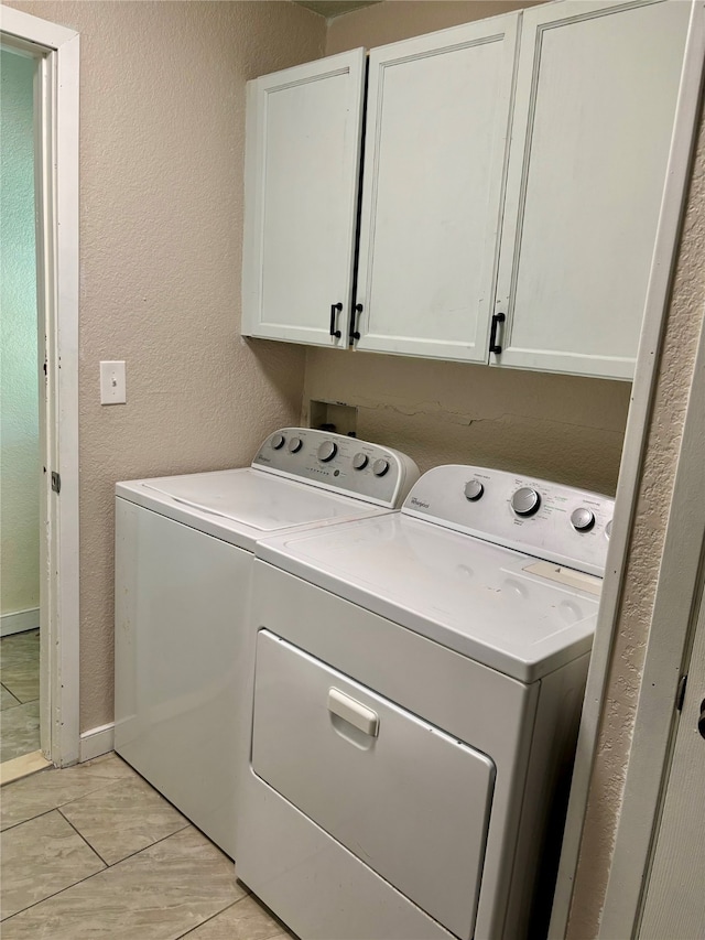 laundry room with cabinets, light tile patterned flooring, and washer and dryer