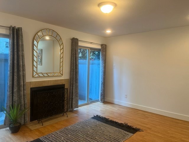 interior space featuring wood-type flooring and a tiled fireplace