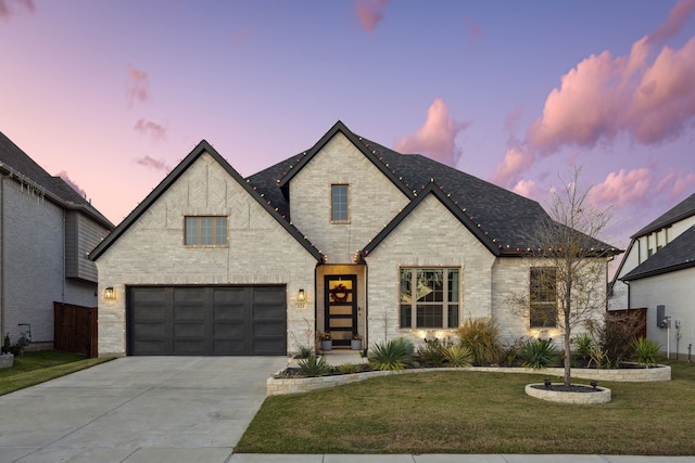 french country inspired facade with a yard and a garage