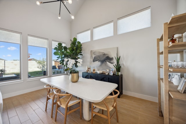 dining room with light wood-type flooring, high vaulted ceiling, and a chandelier