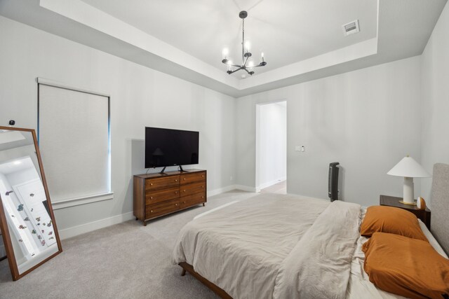 bedroom featuring light carpet, a tray ceiling, and a notable chandelier