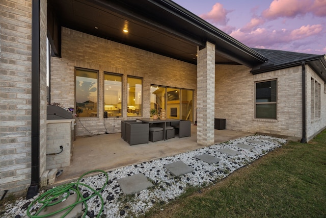 back house at dusk featuring a patio