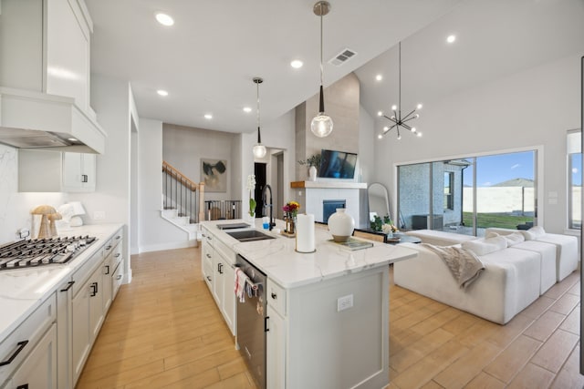 kitchen with white cabinetry, a center island with sink, custom exhaust hood, and sink