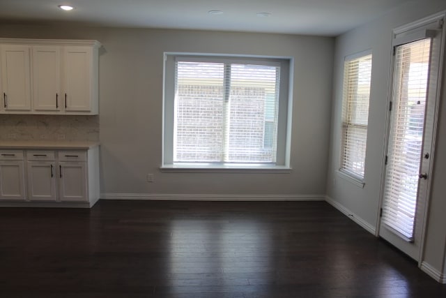 unfurnished dining area featuring a wealth of natural light and dark hardwood / wood-style flooring