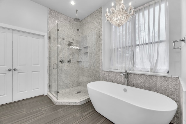 bathroom with shower with separate bathtub and a notable chandelier