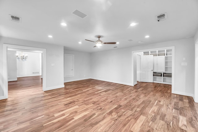 unfurnished living room with ceiling fan with notable chandelier and light wood-type flooring