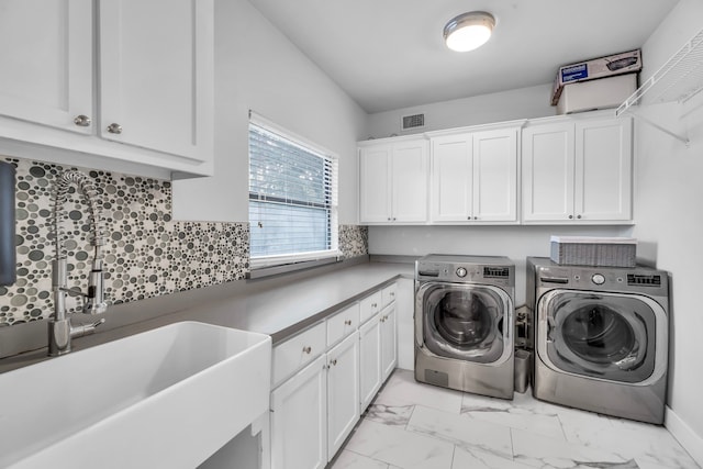 washroom with cabinets, separate washer and dryer, and sink