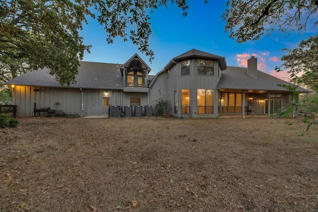 7170 Fm 1830, Argyle, TX 76226 - back of property at dusk featuring board and batten siding, a chimney, a shingled roof, and a balcony