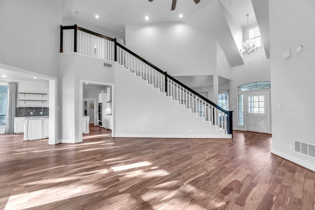 7170 Fm 1830, Argyle, TX 76226 - unfurnished living room with a towering ceiling, stairs, wood finished floors, ceiling fan, and a chandelier