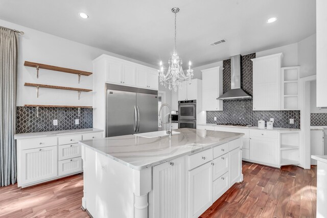 kitchen featuring white cabinets, appliances with stainless steel finishes, sink, and wall chimney range hood