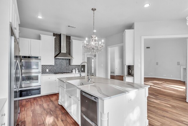 kitchen featuring a center island with sink, white cabinets, dark wood-type flooring, and wall chimney range hood