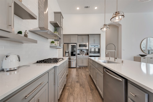 kitchen featuring appliances with stainless steel finishes, gray cabinetry, dark wood-type flooring, sink, and pendant lighting