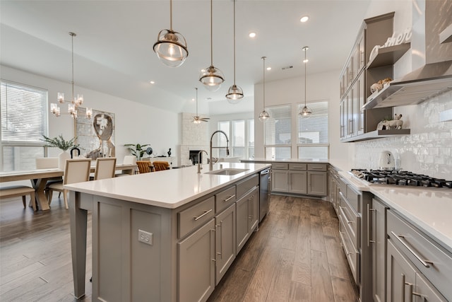 kitchen featuring ceiling fan, sink, a large island with sink, decorative light fixtures, and hardwood / wood-style floors