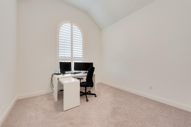 carpeted home office featuring vaulted ceiling