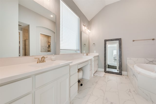 bathroom featuring a relaxing tiled tub, vanity, and vaulted ceiling